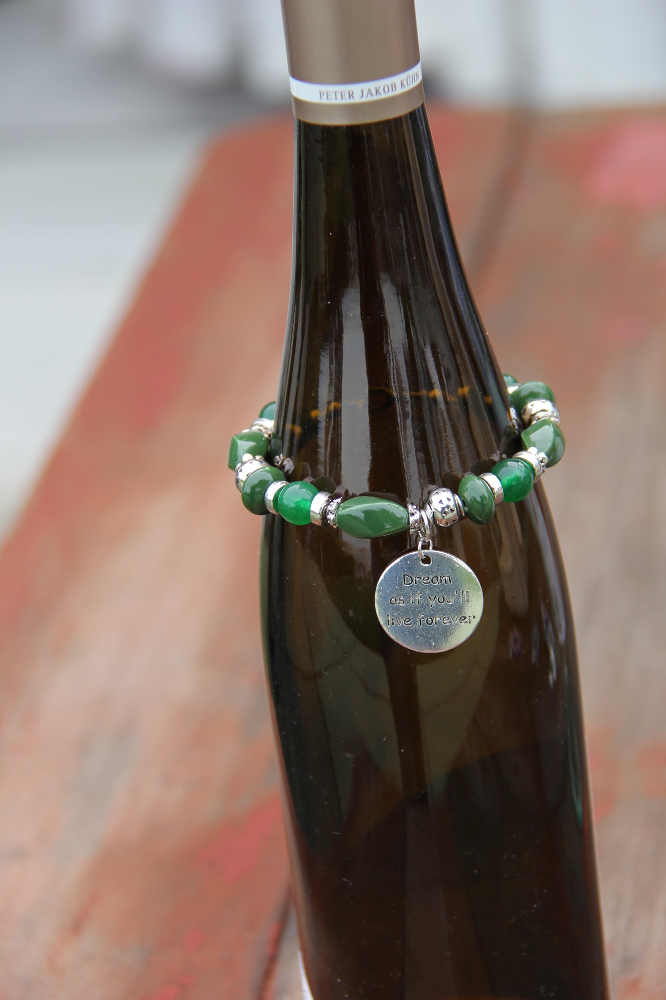 Green beads bottle bracelet with "Dream as if you'll live for ever" charm.